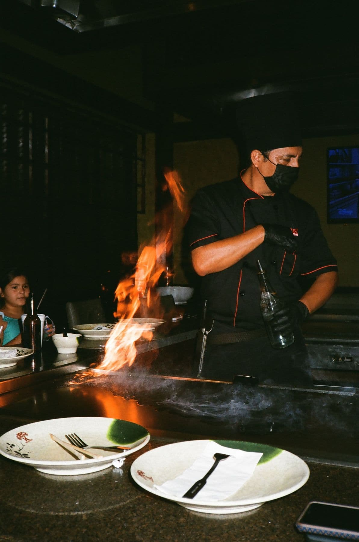 Chef flambéing a dish at an open kitchen during evening service