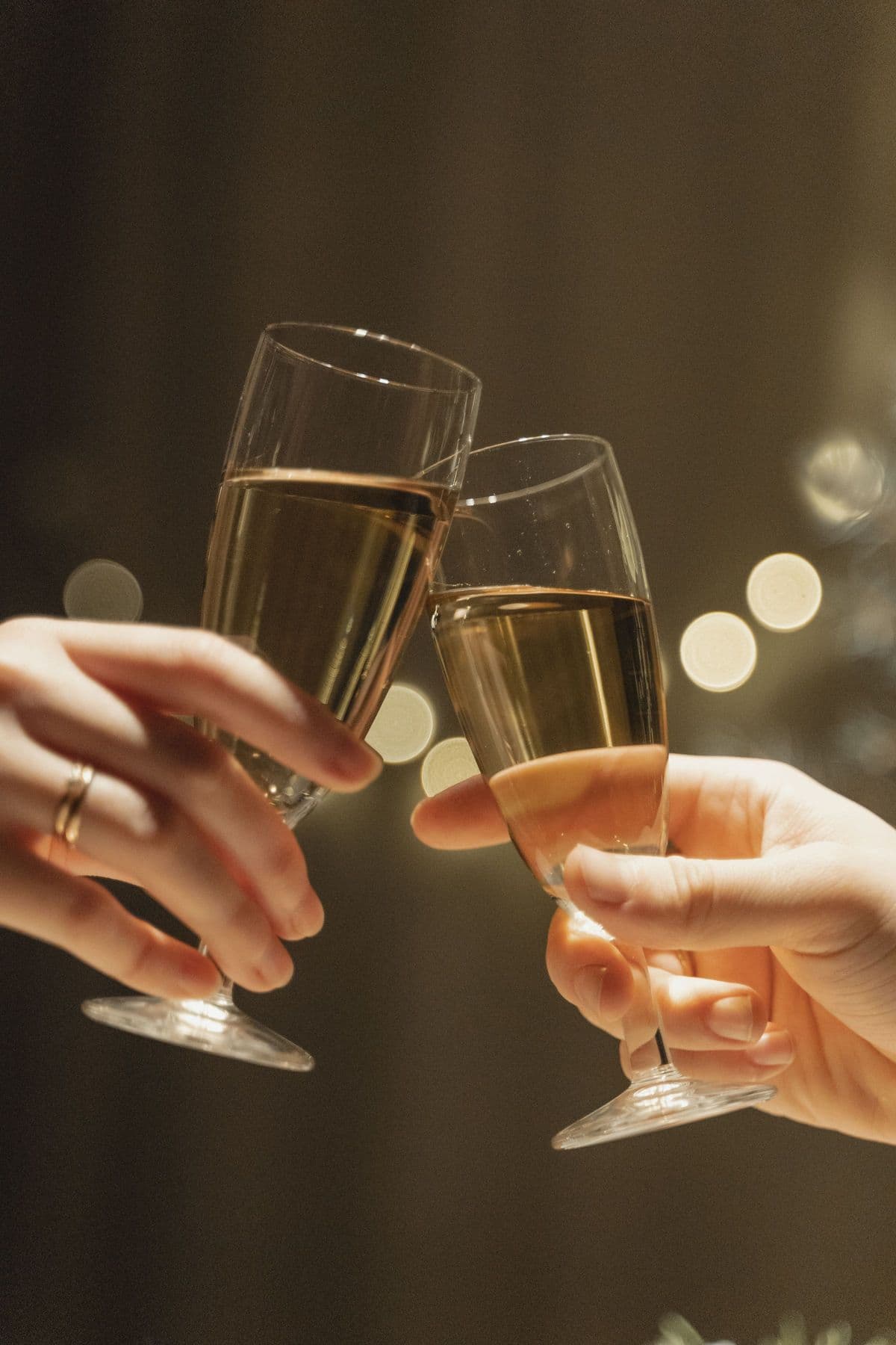 Two champagne glasses meeting in a toast against warm, glowing bokeh