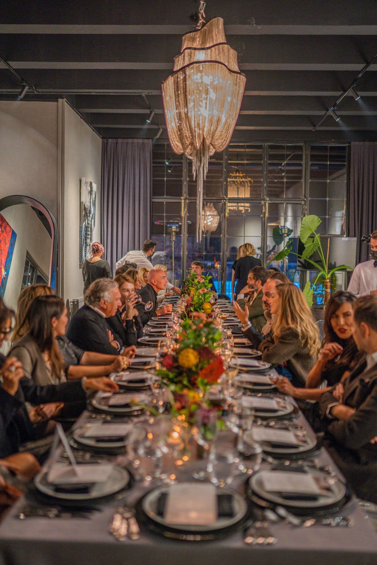 Long banquet table filled with guests beneath a crystal chandelier