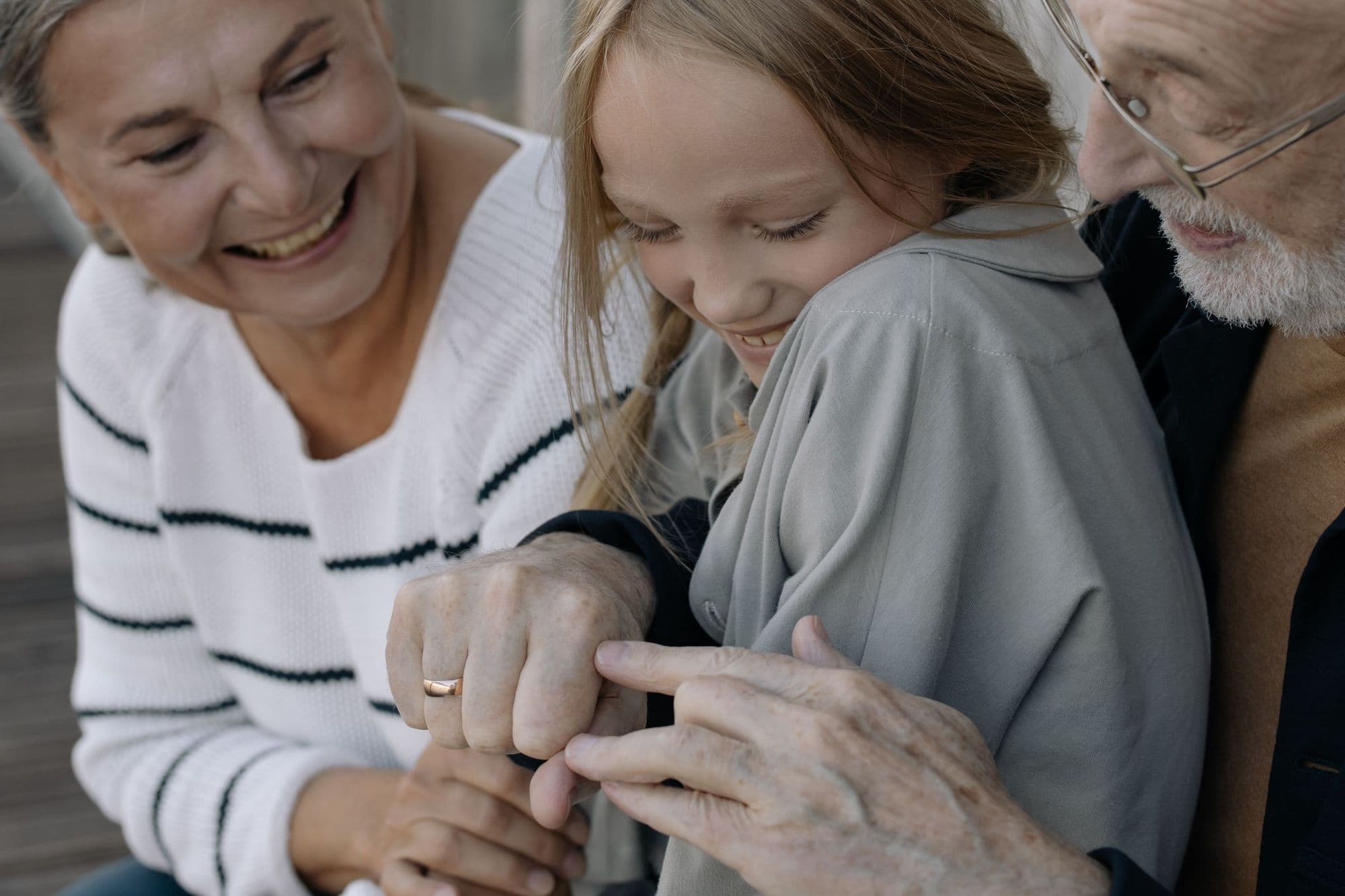 Grandmother and granddaughter laughing together as the grandfather looks on