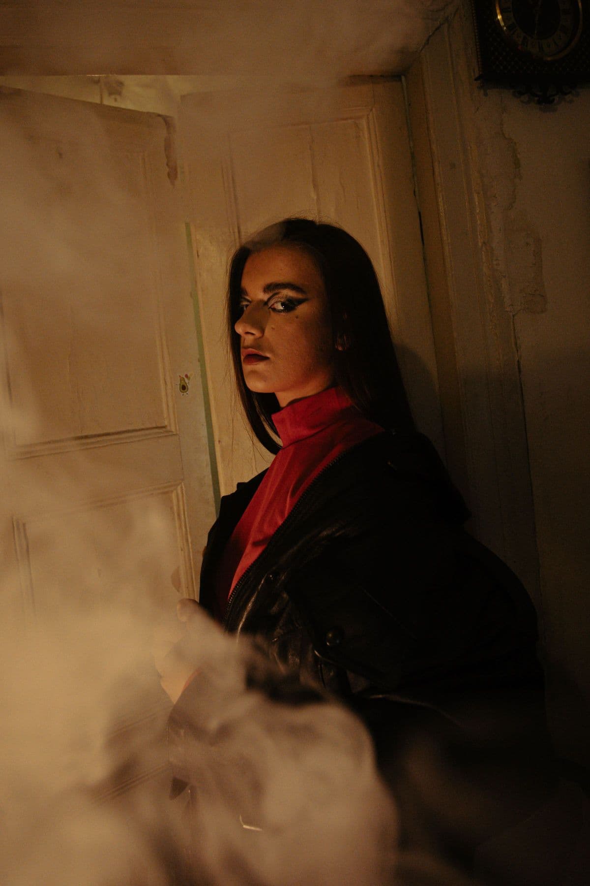 Woman in a red scarf standing amid drifting smoke in a warm interior