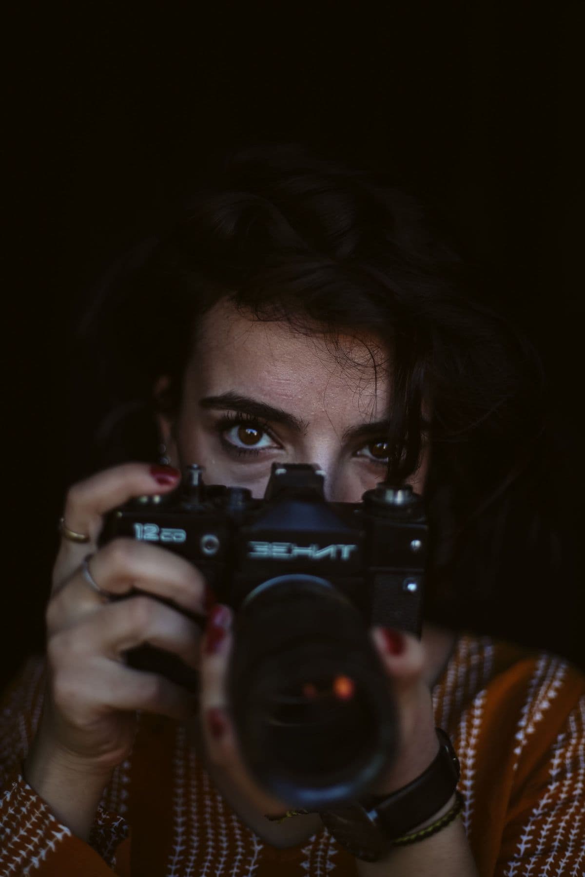 Amara Cole raising her camera to her eye in low, warm light