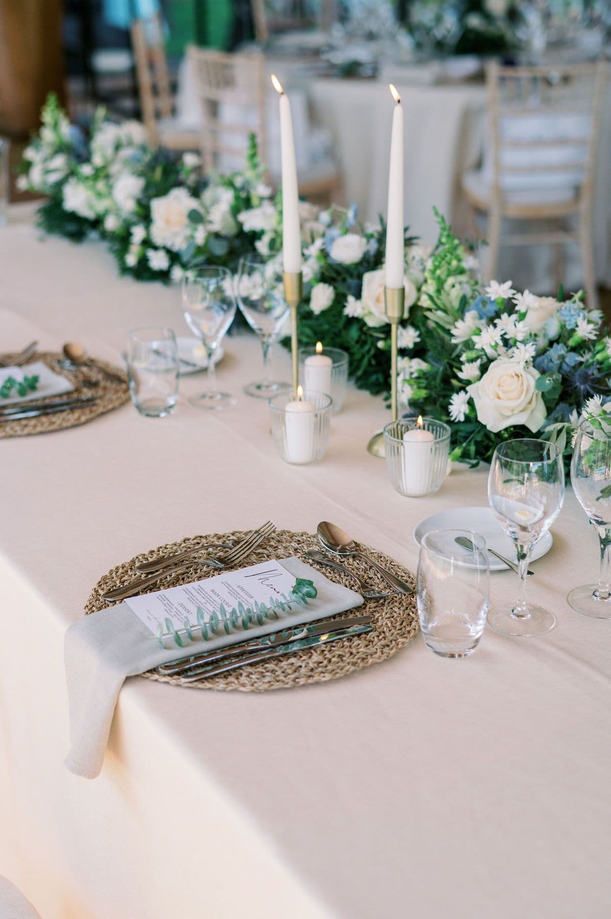 Reception table dressed with eucalyptus, cream florals, and taper candles
